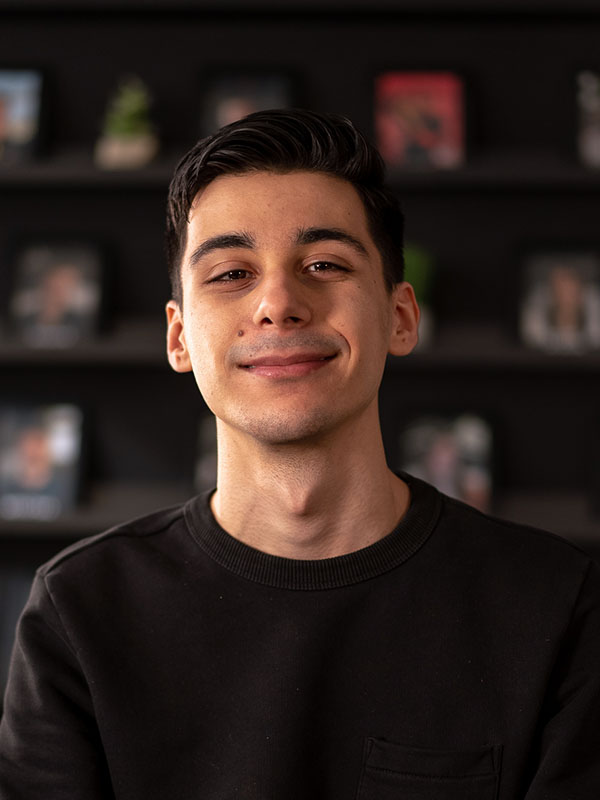 Picture of a smiling Taha with some blurred picture frames on the background
